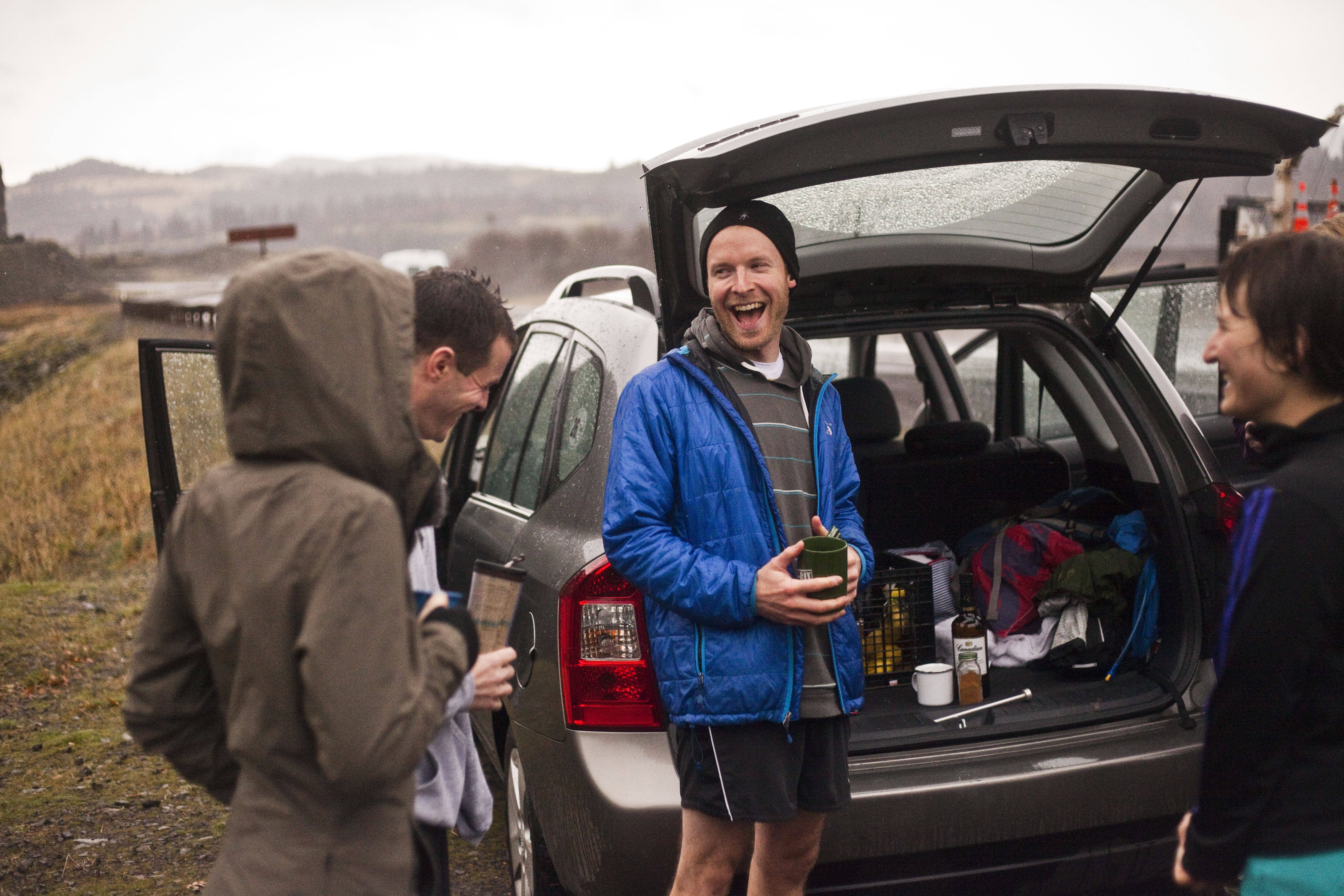 runners gathered around the open back of a car after a trail run in the early territory run co days