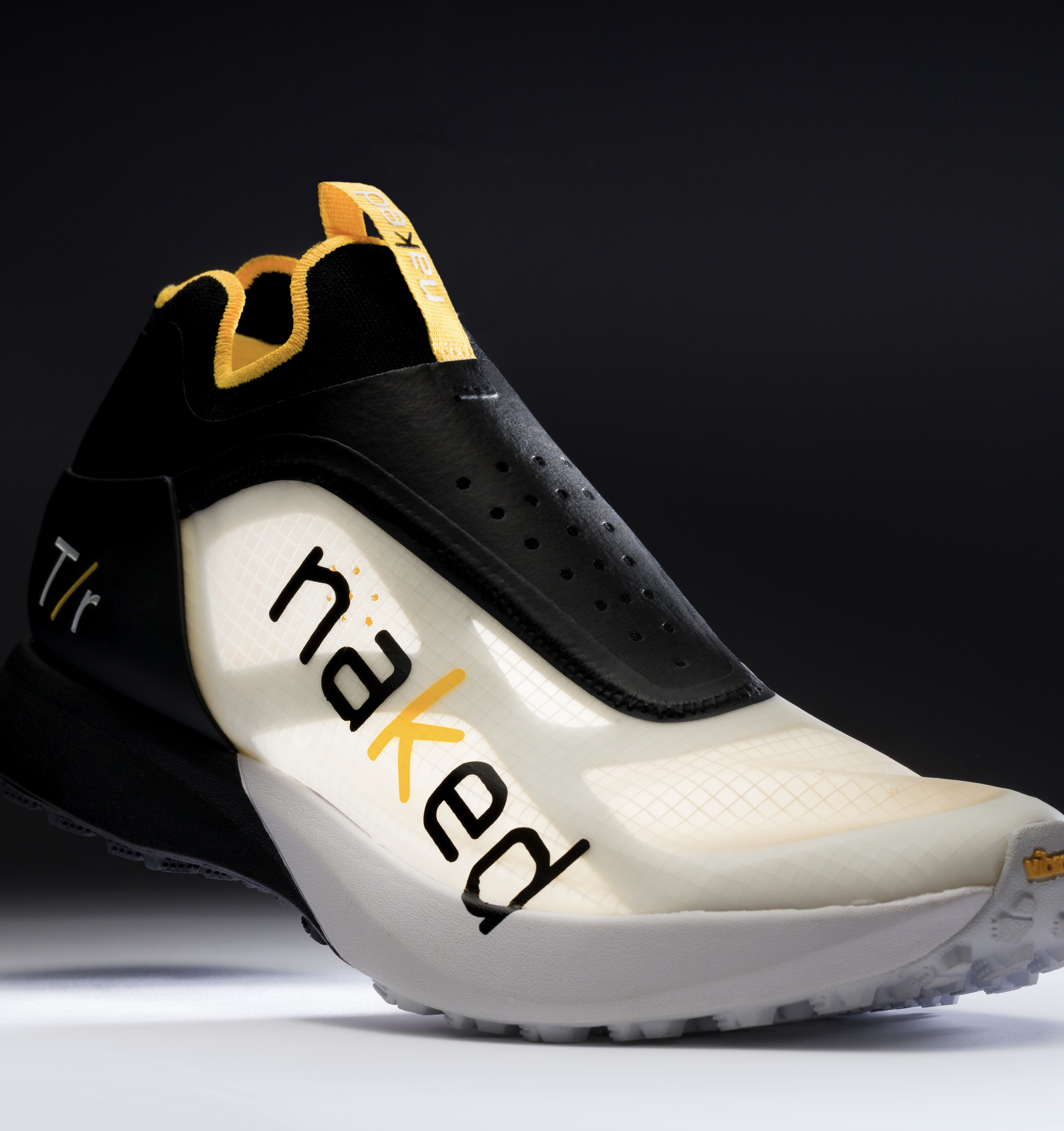 the naked t/r laceless trail running shoe in black and white with a yellow pull tab