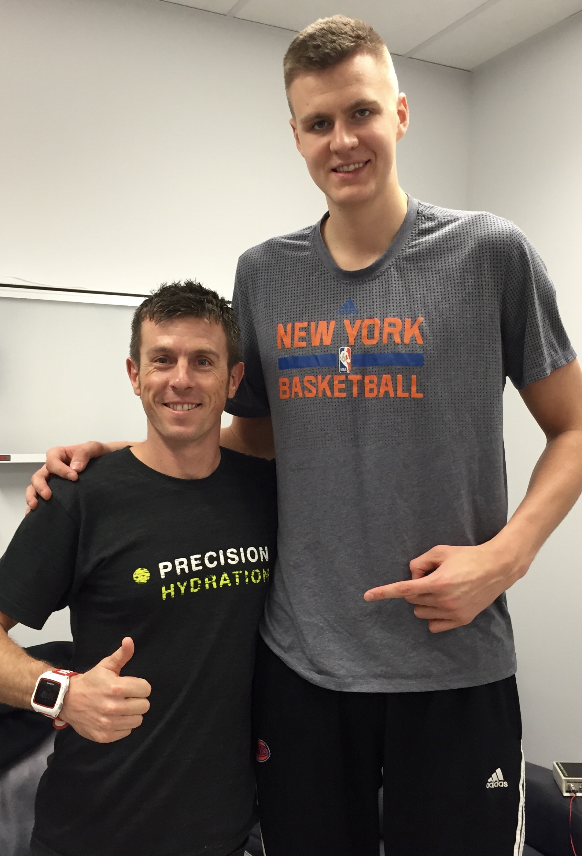 andy blow standing beside kristaps porzingis of the new york knicks, both smiling in a team facility