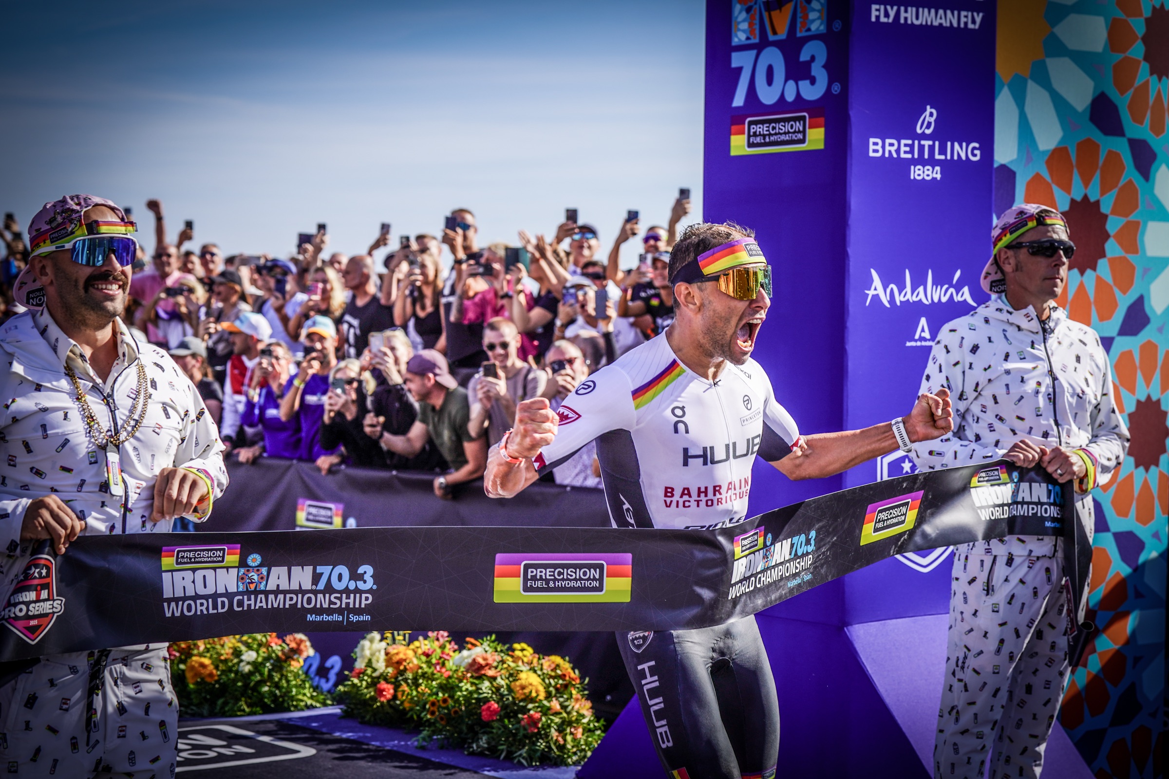 jelle geens breaking the finish tape held by andy blow and jonny tye at the 2025 ironman 70.3 world championship